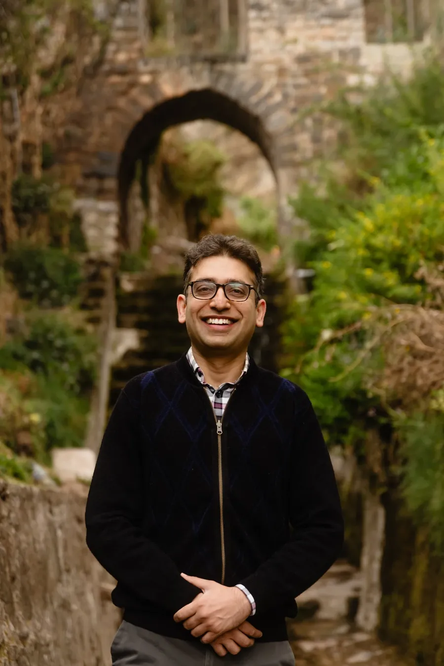 Sameer Vermani smiling, standing before a stone archway